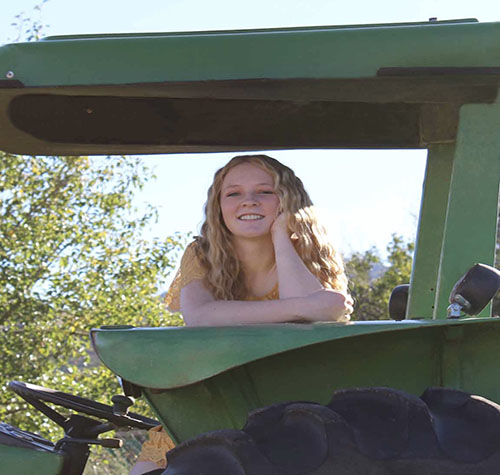 Kassidy sitting on a tractor for a photo